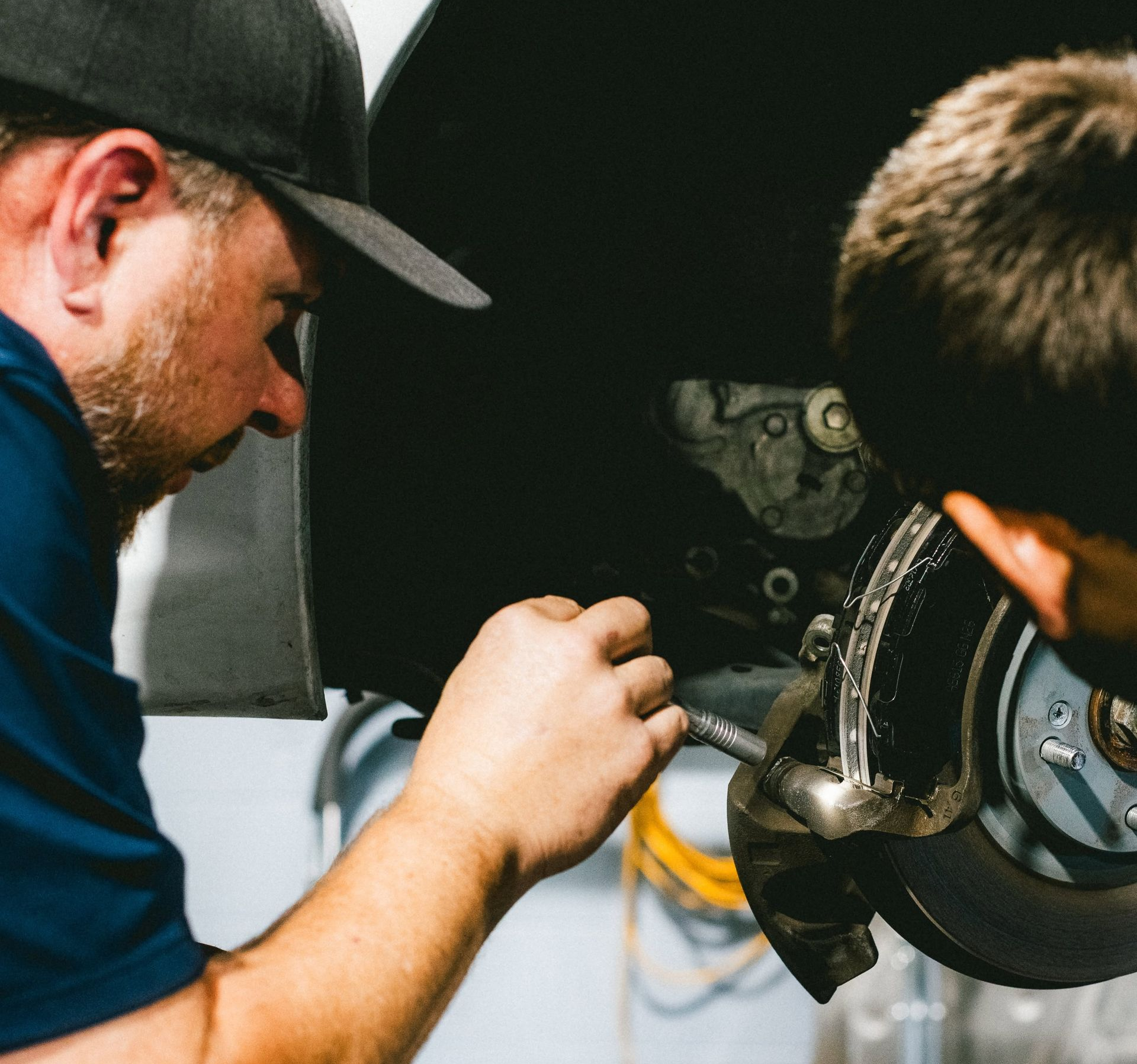 Mechanic working on a car brake assembly with tools in a workshop