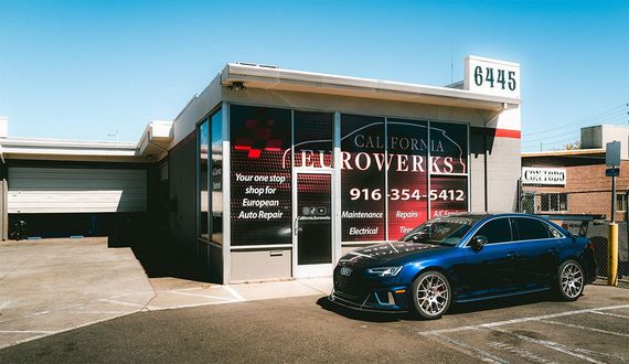Storefront with “JACK BROKERS” sign and a blue car parked outside under a clear sky.