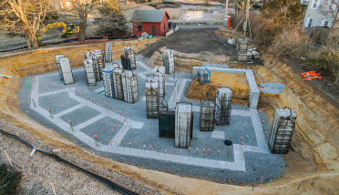 An aerial view of a construction site with a red barn in the background.