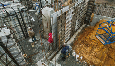 A group of construction workers are working on a wall at a construction site.