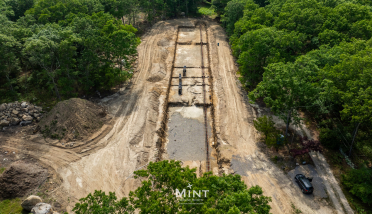 An aerial view of a construction site with a car parked on the side of the road.
