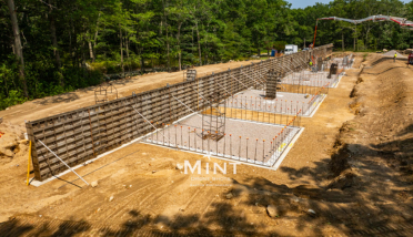 A large concrete wall is being built in the middle of a dirt field.