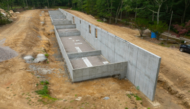 An aerial view of a concrete wall in the middle of a dirt road.
