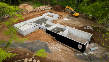 An aerial view of a house under construction with a bulldozer in the background.