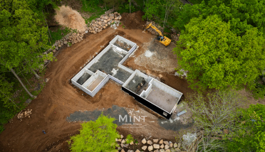 An aerial view of a house being built in the middle of a forest.