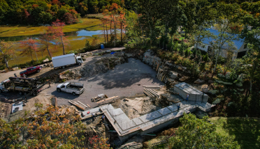 An aerial view of a house under construction in the middle of a forest.