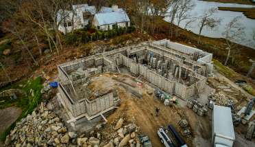 An aerial view of a house under construction next to a body of water.