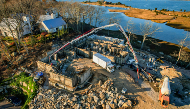 An aerial view of a house under construction next to a body of water.