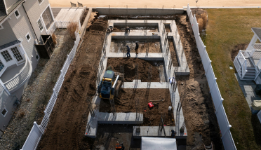 An aerial view of a construction site with a house in the background.