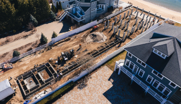 An aerial view of a house under construction next to a body of water.