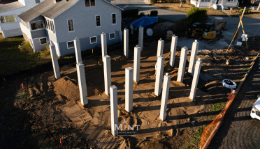 An aerial view of a house under construction with a lot of pillars in the dirt.