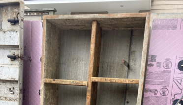A wooden cabinet is sitting on top of a concrete wall.