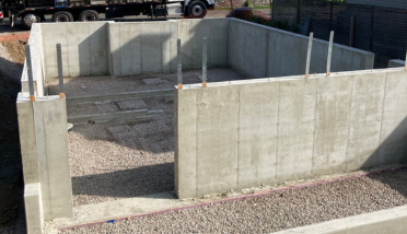 A concrete wall is being built next to a gravel road.