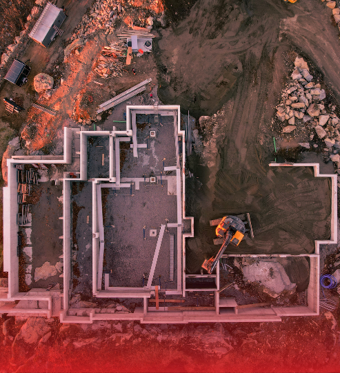 An aerial view of a building under construction with a red background.