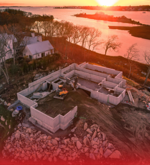 An aerial view of a house under construction next to a body of water.