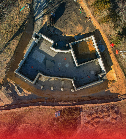 An aerial view of a house under construction with a red background