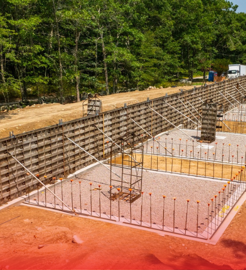 A large concrete wall is being built in the middle of a forest.
