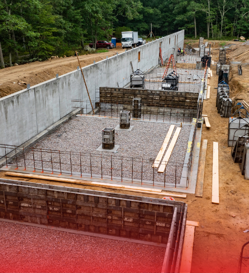 A large concrete wall is being built on a construction site.