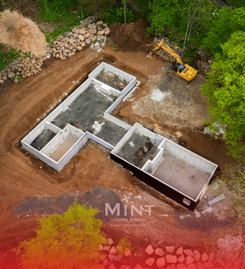 An aerial view of a house under construction with a bulldozer in the background.