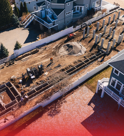 An aerial view of a construction site with a house in the background