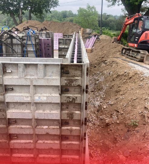 A construction site with a bulldozer and a concrete wall being built.
