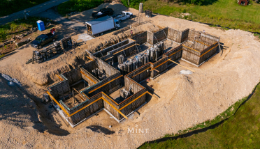 An aerial view of a house under construction in a dirt field.