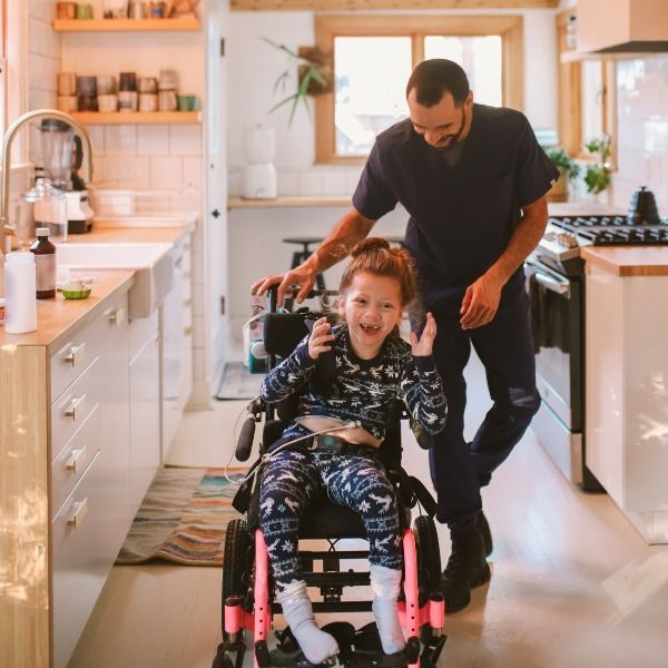 A Man Pushes a Little Girl in A Wheelchair in A Kitchen — Wonder Care Australia Pty Ltd in Kearneys Spring, QLD