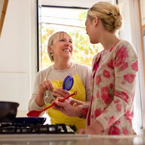 Two Women Are Standing Next to Each Other in A Kitchen Preparing Food — Wonder Care Australia Pty Ltd in Kearneys Spring, QLD