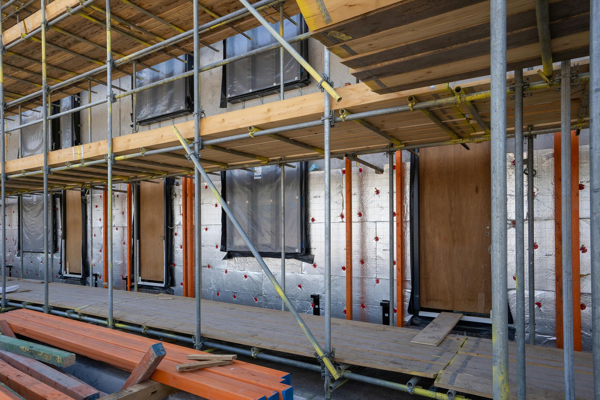 Scaffolding around a building / home under construction, featuring newly installed windows