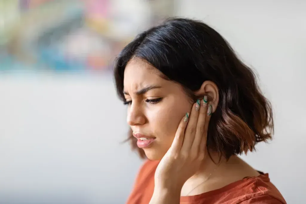 Woman holding her ear because she has an ear infection.
