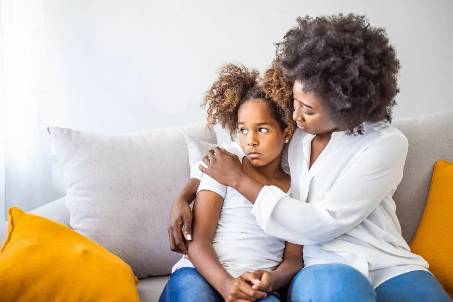 A woman and a little girl are sitting on a couch.