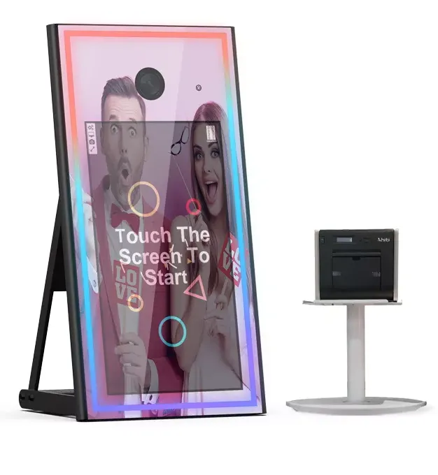 A photo booth mirror with a touch screen, a printer on a stand, and a couple taking a picture.