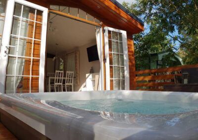 Hot tub on a deck, with open doors to a cabin.