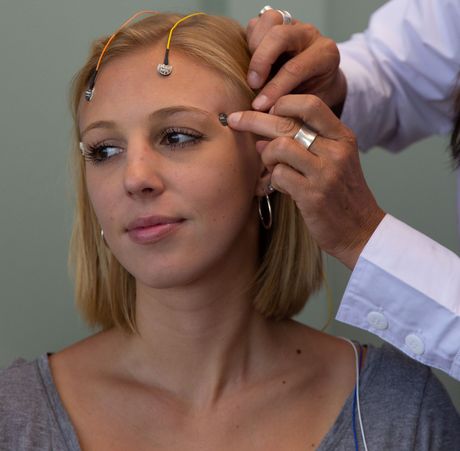 Person receiving an eyebrow exam while a clinician adjusts sensors on the forehead
