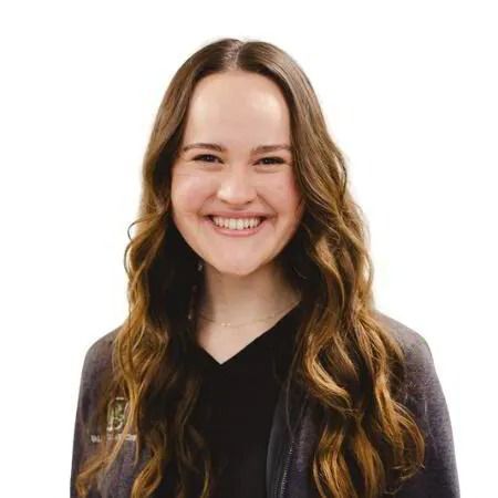 Smiling woman with long wavy hair wearing a black top against a white background