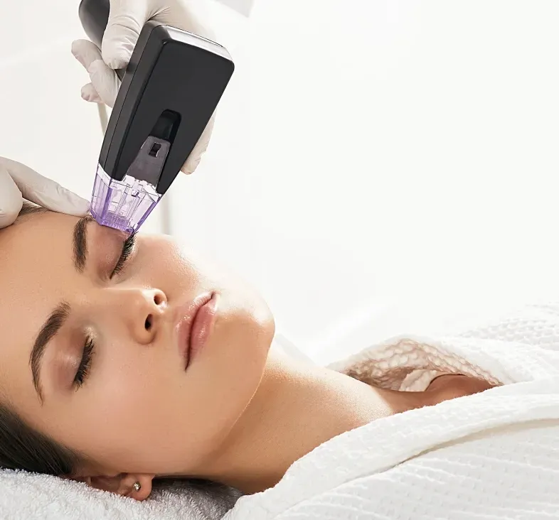 Woman receiving a facial treatment with a handheld device on her forehead, lying on a spa bed
