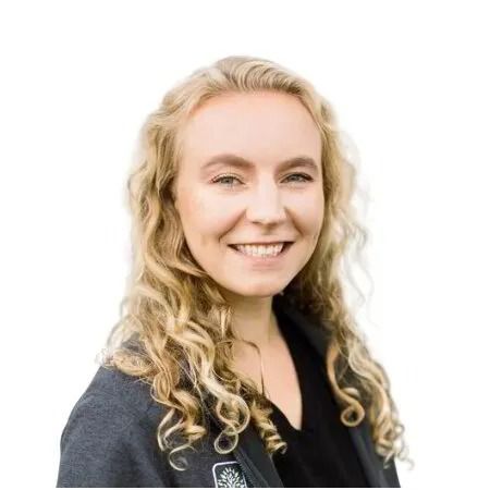 Smiling blonde woman in a dark blazer against a white background