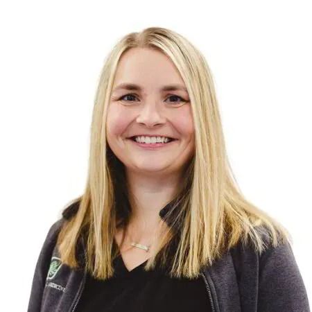 Smiling blonde woman in a dark jacket against a white background