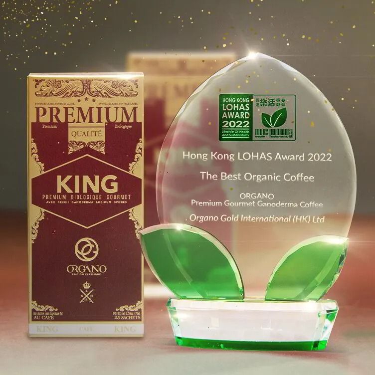 Premium King coffee box beside green glass trophy award on a gold background