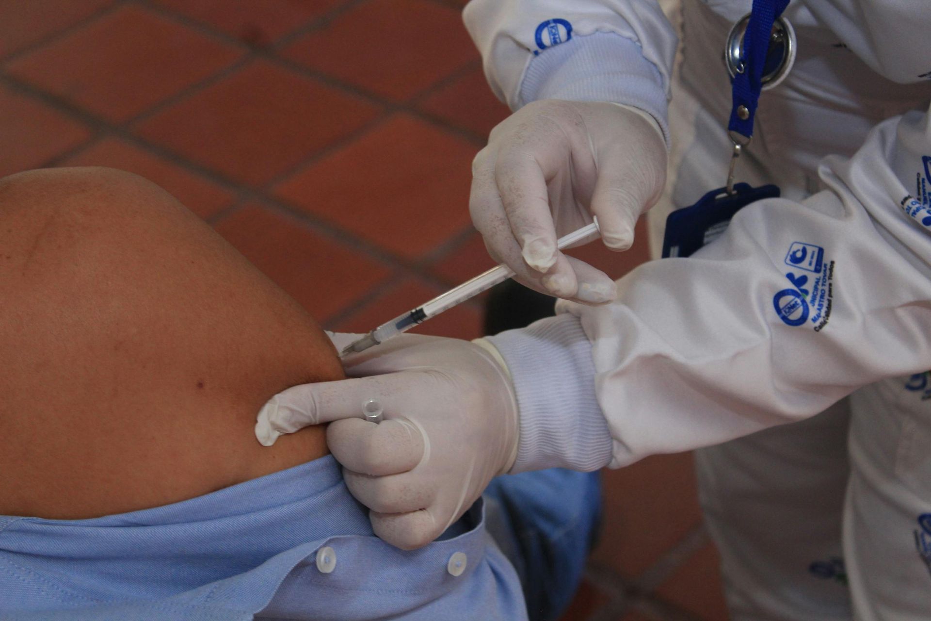 Healthcare worker giving a syringe injection in a patient’s lower back/hip area