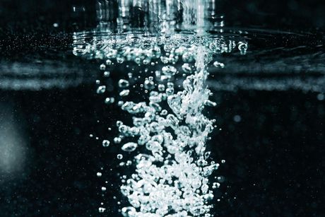 White bubbles rising through dark water beneath the surface