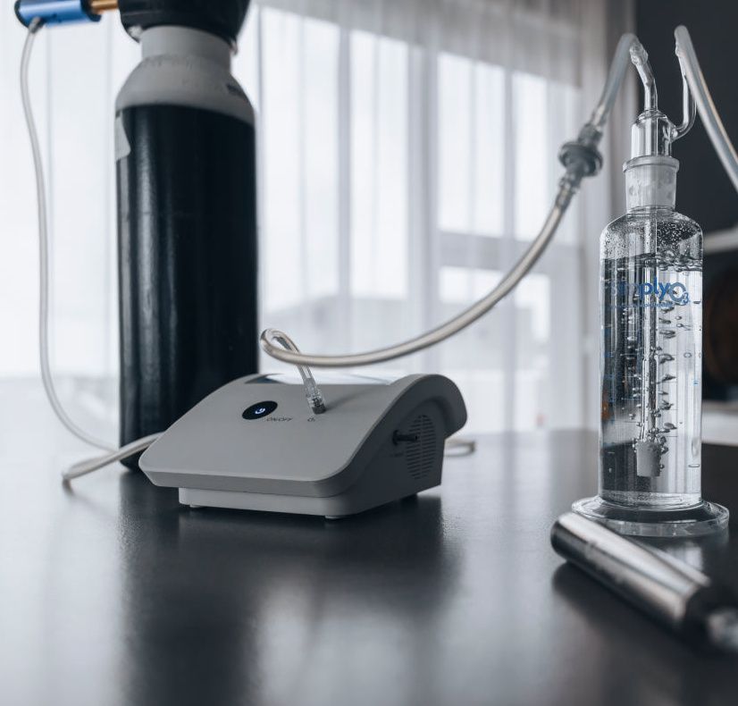 Breathing machine and clear oxygen bottle on a table in a bright clinical room
