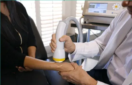 Doctor using an ultrasound probe on a patient’s forearm in a clinic room