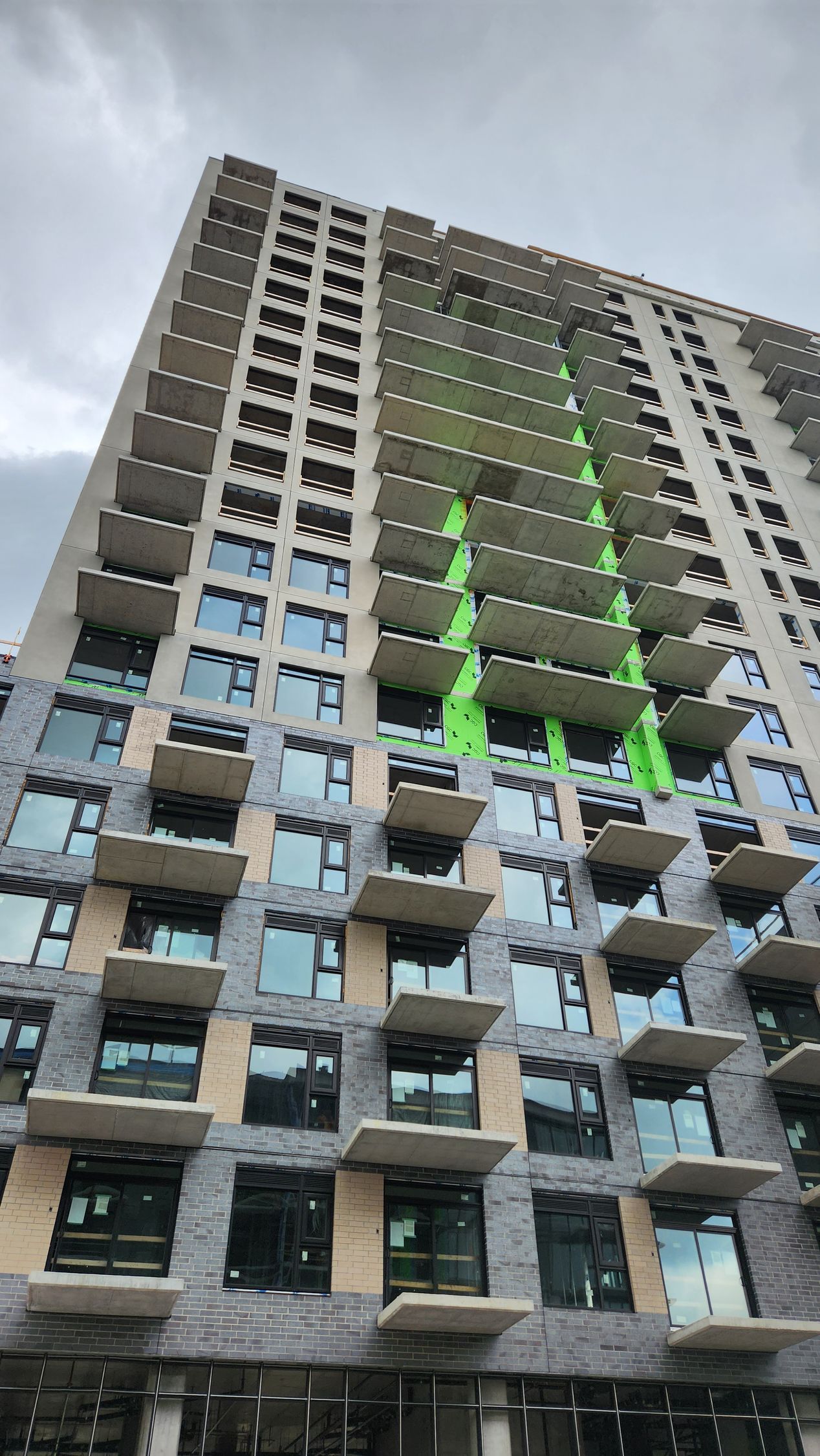 Immeuble d'appartements de grande hauteur avec une bande verticale de lumières vertes vives sur la façade