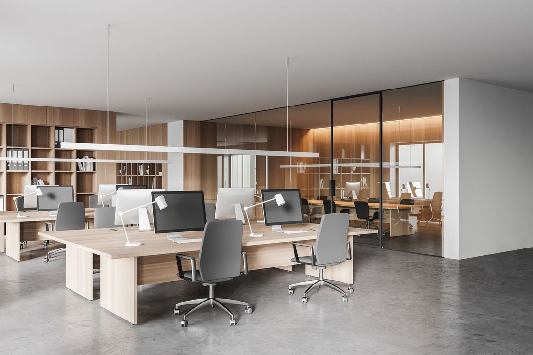 Bureau moderne à aire ouverte avec bureaux, ordinateurs, chaises grises et salles de réunion vitrées