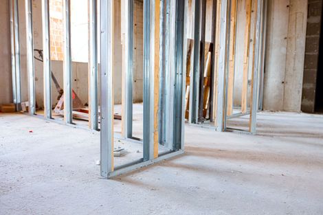 Intérieur inachevé avec ossature métallique, montants en bois apparents et sol en béton