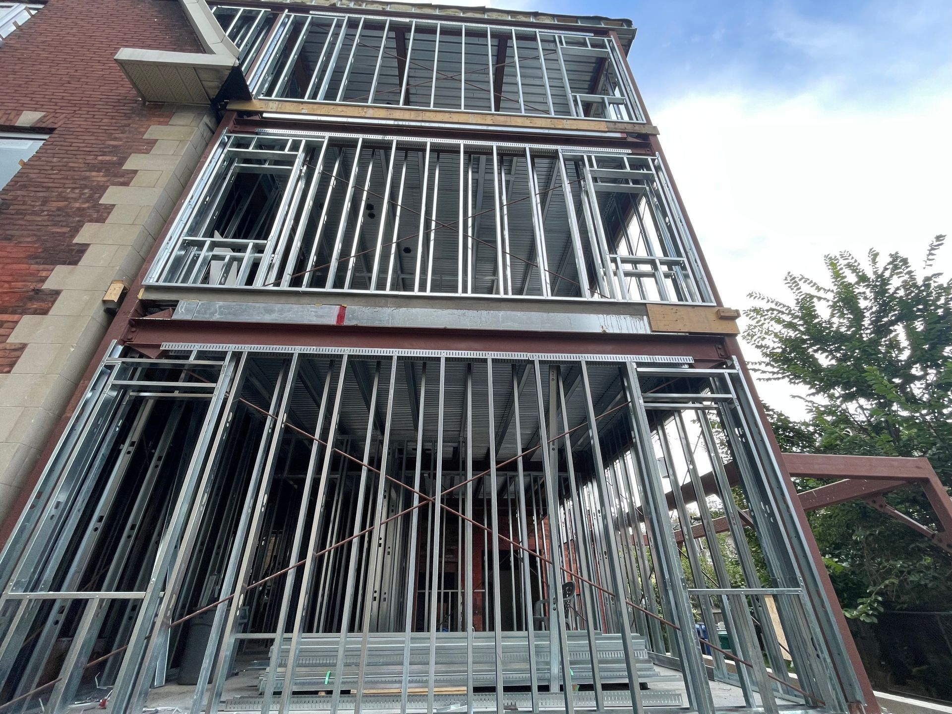 Immeuble en briques à plusieurs étages, avec des barreaux métalliques aux fenêtres et à l'entrée, vu d'en bas