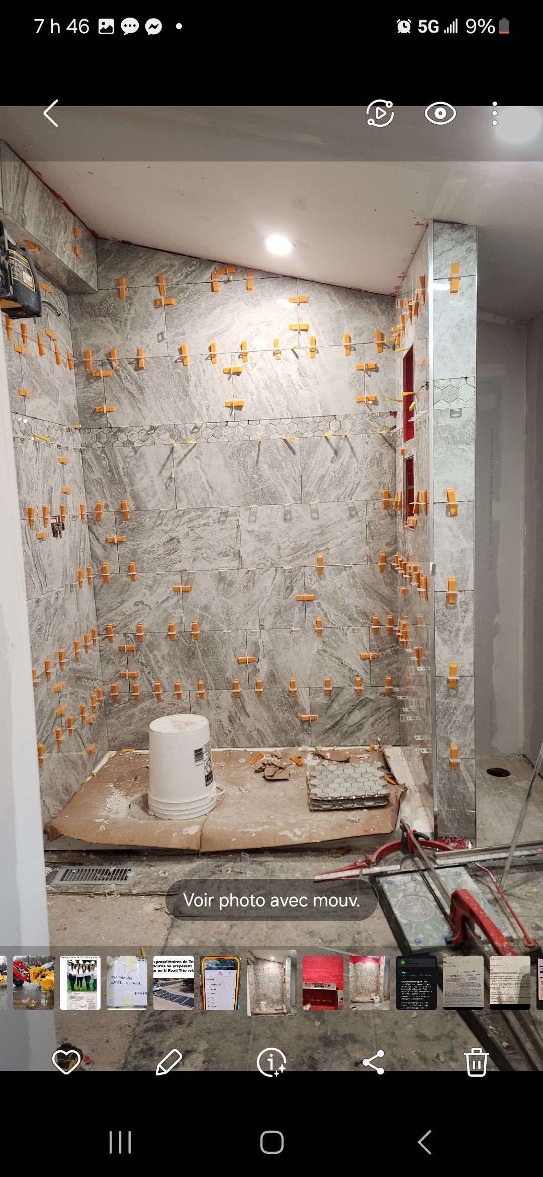 Mur de salle de bain partiellement démoli, laissant apparaître des tuyaux, des débris et des restes de carrelage lors de travaux de rénovation.