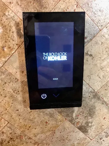 Black touchscreen control panel on a marble wall, showing The Book of Boba Fett screen with power icon.