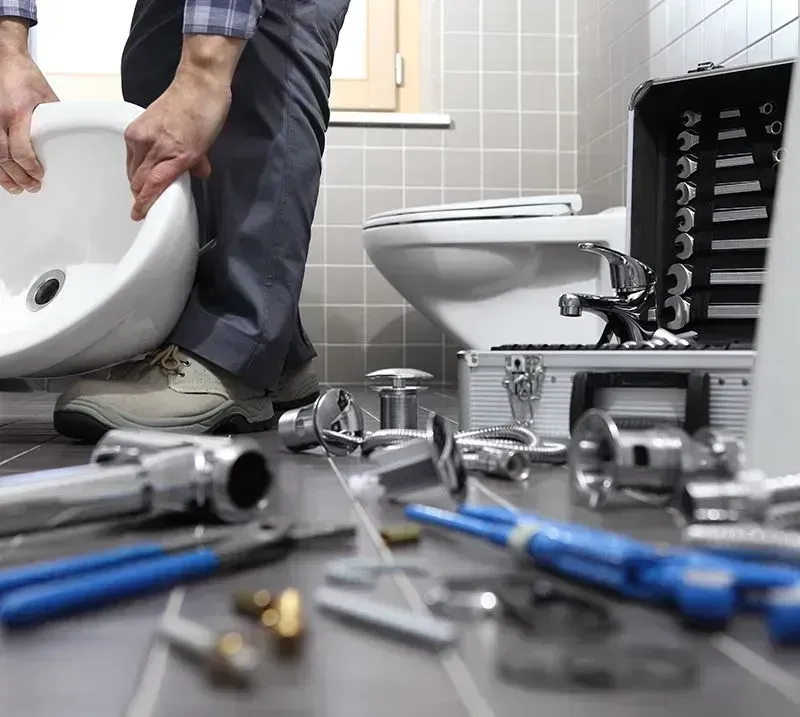 Technician installing a toilet in a bathroom, with tools scattered on the floor.